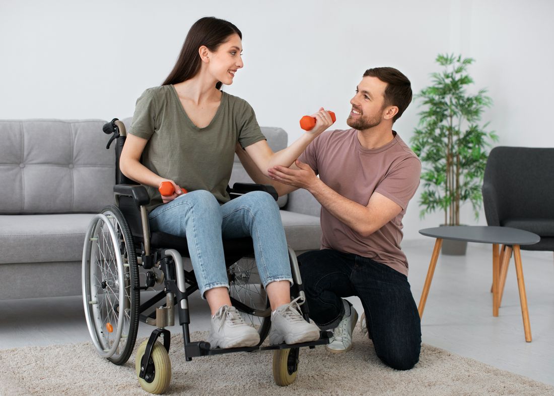 A Direct Support Professional assisting a participant with light exercise at home