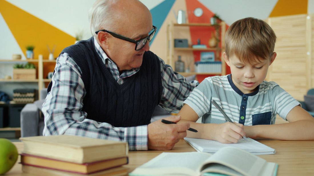 A grandfather helping his grandson with schoolwork at home
