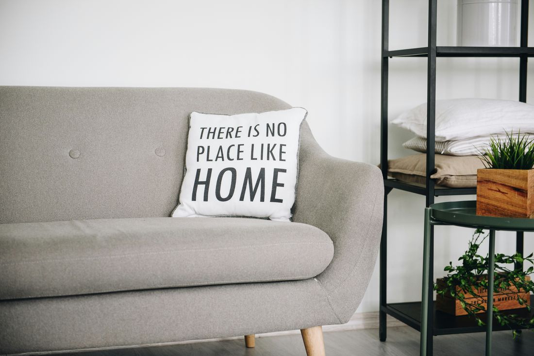 A cozy living room with a pillow that reads 'There is no place like home'