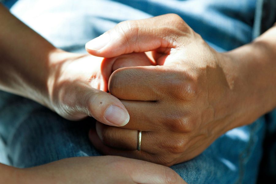 Close-up of two people holding hands, representing care and support